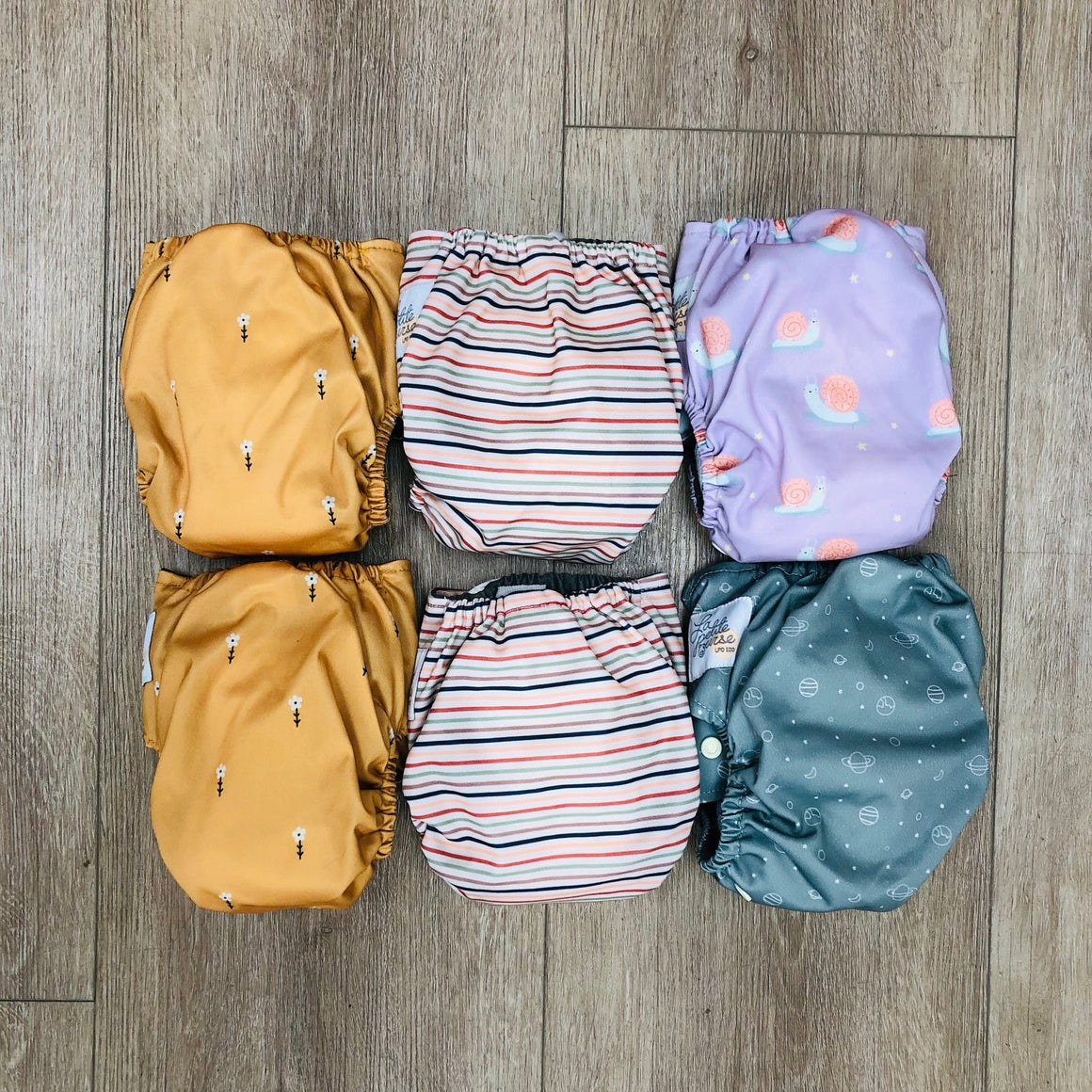 Set of patterned La Petite Ourse newborn cloth diapers on a wooden surface