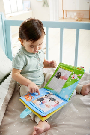 toddler enjoying the photos in the First Photo Album Friends of the Enchanted Forest by Haba